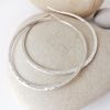 Hammerd silver hoops. This hoops are large and have a trendy look.
